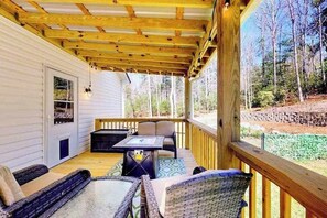 Eine überdachte Terrasse mit Gartenmöbeln, einem Tisch und Blick auf den umliegenden Wald.