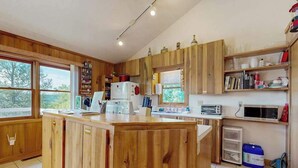 Une cuisine avec des meubles de rangement en bois, un îlot central, un four à micro-ondes et un réfrigérateur.