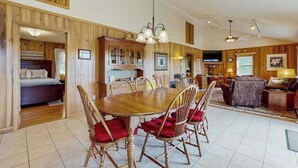 Un vaste espace de vie comprenant une table à manger en bois, des chaises et un téléviseur.