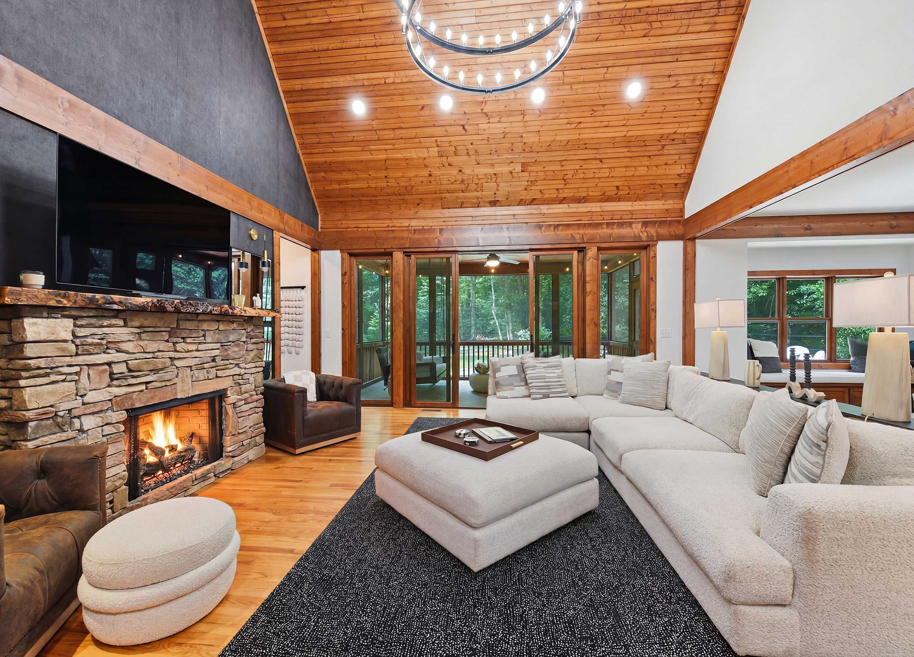A spacious living room with a stone fireplace, a leather sofa, and a large sectional couch.