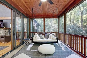 A modern interior with a wooden ceiling, large windows, a sofa, and a stone fireplace. - Charming house in Brevard with heated outdoor pool, tennis court, and a gym (Brevard)