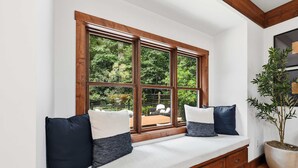 A room with a built-in bench along a large window overlooking a garden. - Charming house in Brevard with heated outdoor pool, tennis court, and a gym (Brevard)