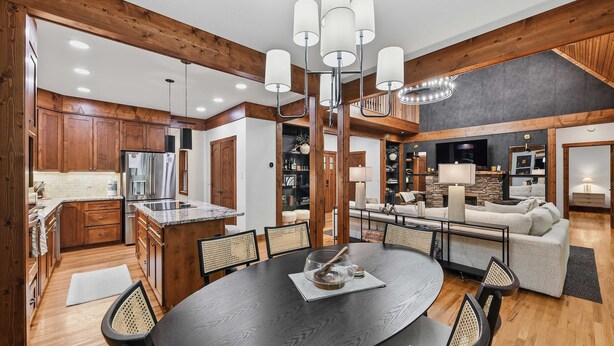 A modern kitchen with wooden cabinets, a central island, and a dining area with a round table and chairs. - Charming house in Brevard with heated outdoor pool, tennis court, and a gym (Brevard)