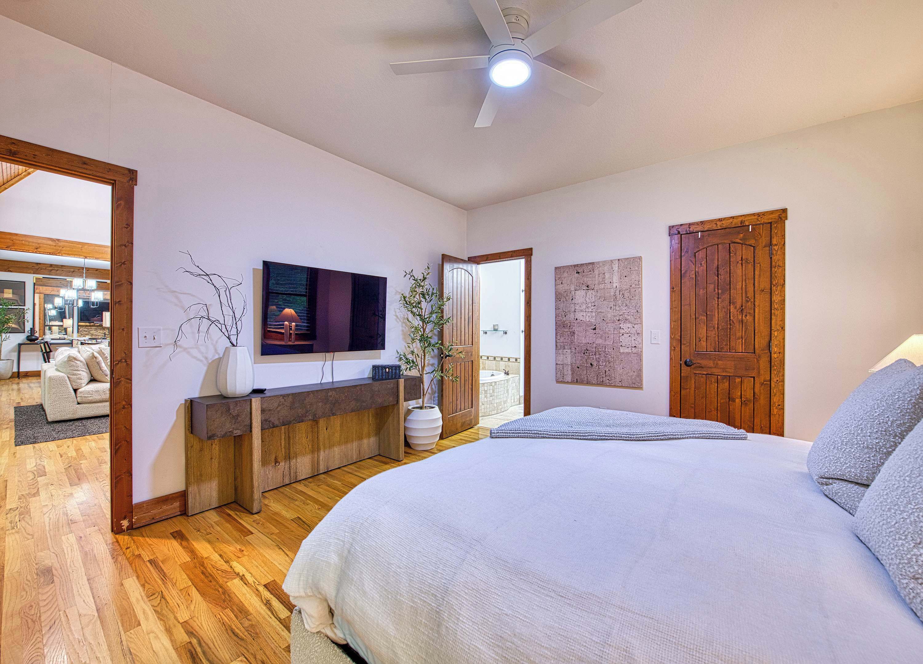 A bedroom with a bed, a TV, a wooden door, and a bathroom visible through an open door.
