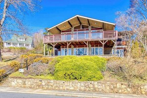 A two-story building with a balcony, stone wall, and surrounding vegetation. - Morris Villa Lower (Lake Junaluska)