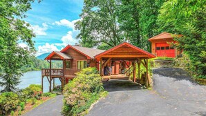 Mökki, jossa on kuisti, autotalli ja näkymä järvelle.