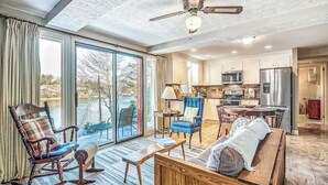 A spacious living room with a large sliding glass door, a ceiling fan, and a view of the outdoors. - Armstrong Apartment (Lake Junaluska)