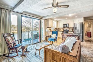 A spacious living room with a large sliding glass door, a ceiling fan, and a view of the outdoors. - Armstrong Apartment (Lake Junaluska)