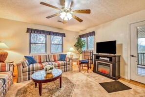 Ein Wohnzimmer mit Sofa, Fernseher, Kamin und Deckenventilator.