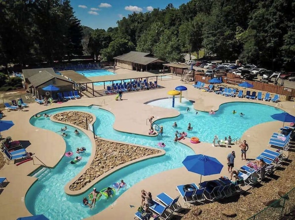A pool area with multiple swimming sections, lounge chairs, and umbrellas. - Family Escape at Rumbling Bald with Firepit, Games & Fiber Internet (Lake Lure)