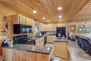 Ein Holzblockhaus-Interieur mit Küche, Essbereich und Wohnzimmer mit Kamin.