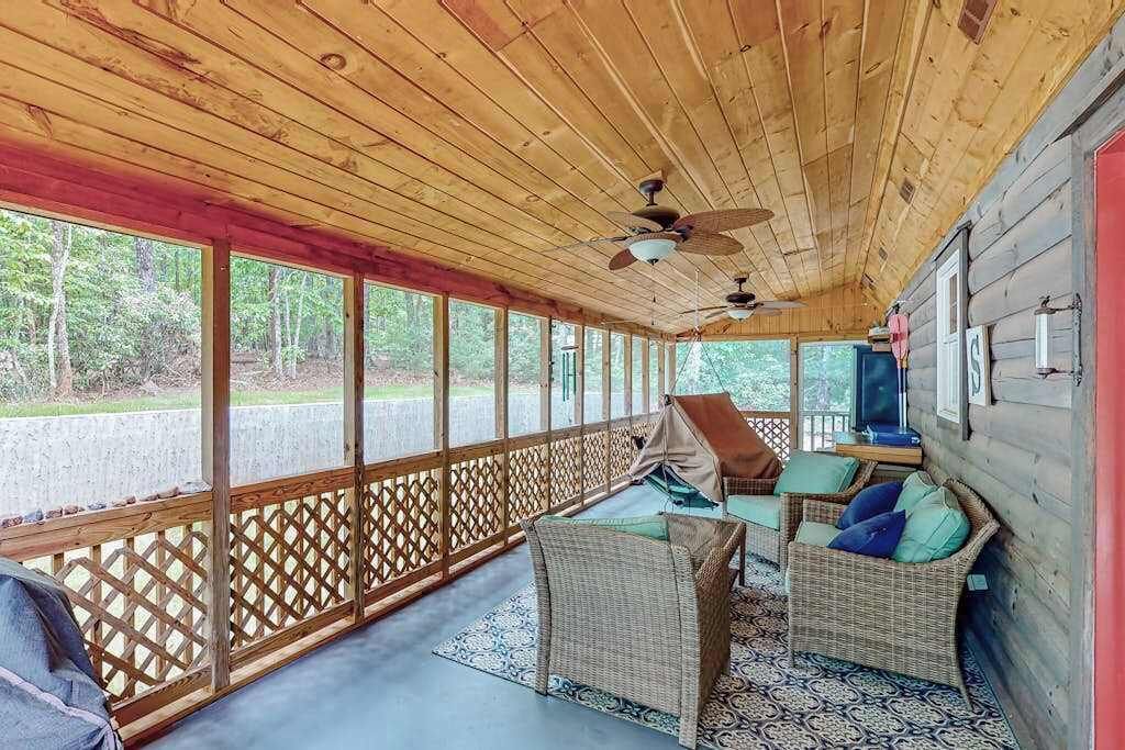 Eine überdachte Veranda mit Korbmöbeln, Deckenventilatoren und Blick ins Freie.