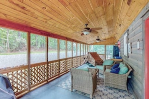 Eine überdachte Veranda mit Korbmöbeln, Deckenventilatoren und Blick ins Freie.