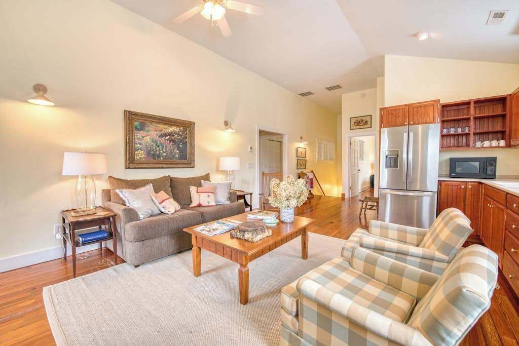 Una sala de estar con sofá, sillón, mesa de centro y una zona de cocina con refrigerador y microondas.