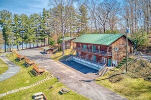 A cabin with a green roof, a covered porch, and a dock extending into a lake. - Campground Cabin (Lake Junaluska)