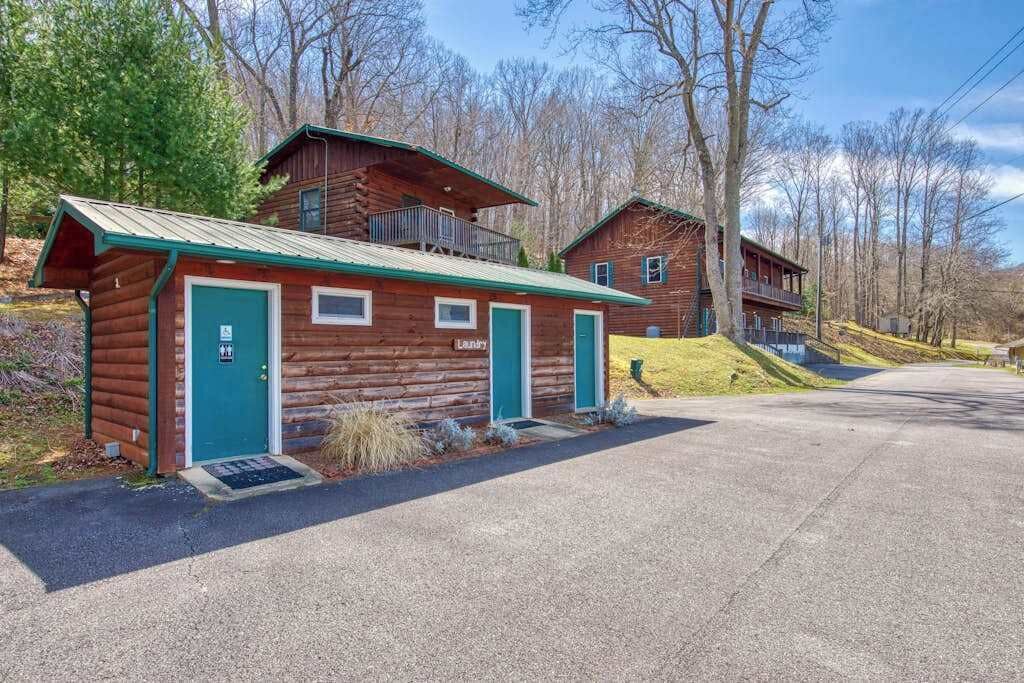 A rustic log cabin with a green door, a balcony, and a small porch area.