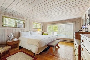 Ein Schlafzimmer mit Holzwandverkleidung, einem Bett, einem Nachttisch, einer Lampe und einer Bank.