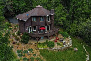 A multi-level wooden house with a deck, surrounded by dense forest. - Bright Brevard House w/ Fireplaces, Jetted Tub, Fire Pit & Bike Storage (Brevard)