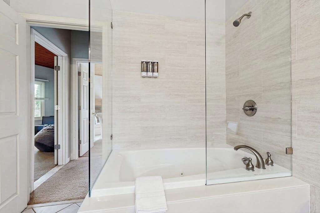 A modern bathroom with a glass-enclosed shower, a large bathtub, and a visible toilet.
