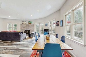 A spacious living area with a fireplace, a long wooden table, and a comfortable seating arrangement. - Bright Brevard House w/ Fireplaces, Jetted Tub, Fire Pit & Bike Storage (Brevard)