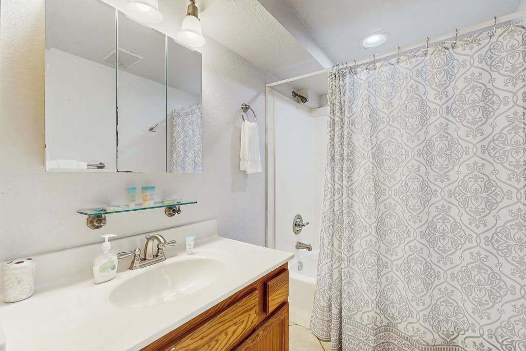 A bathroom with a white sink, mirror, and shower curtain.