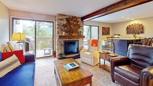 Amplia sala de estar con chimenea, un sofá, una mesa de centro y una zona de comedor.