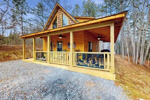 Eine Holzhütte mit Veranda, Schornstein und einem Schotterweg.