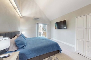 Ein Schlafzimmer mit einem Bett, einem Fernseher, einem Nachttisch und einem Fenster.