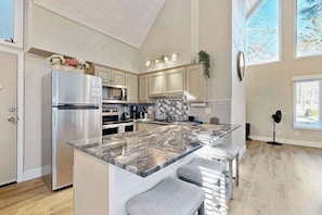 A modern kitchen with a large island, stainless steel appliances, and a view of the outdoors. - Charming Sapphire, NC Condo: Cozy, Dog-Friendly, Pool, Golf Course, & More (Sapphire)