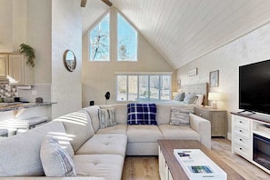 A modern living room with a sectional sofa, a coffee table, a TV, and a fireplace. - Charming Sapphire, NC Condo: Cozy, Dog-Friendly, Pool, Golf Course, & More (Sapphire)