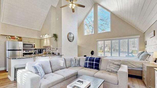 A spacious living area with a large sectional sofa, a coffee table, and a kitchen in the background.
