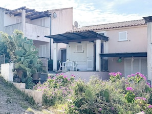 A residential building with a patio, outdoor seating, and a cactus plant. - Ostrica Apartment (Lumio)
