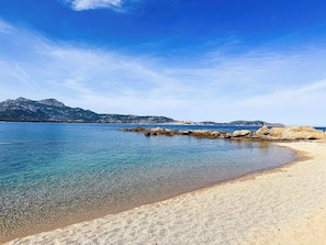 A beach with clear water, rocky shoreline, and distant mountains. - Ostrica Apartment (Lumio)