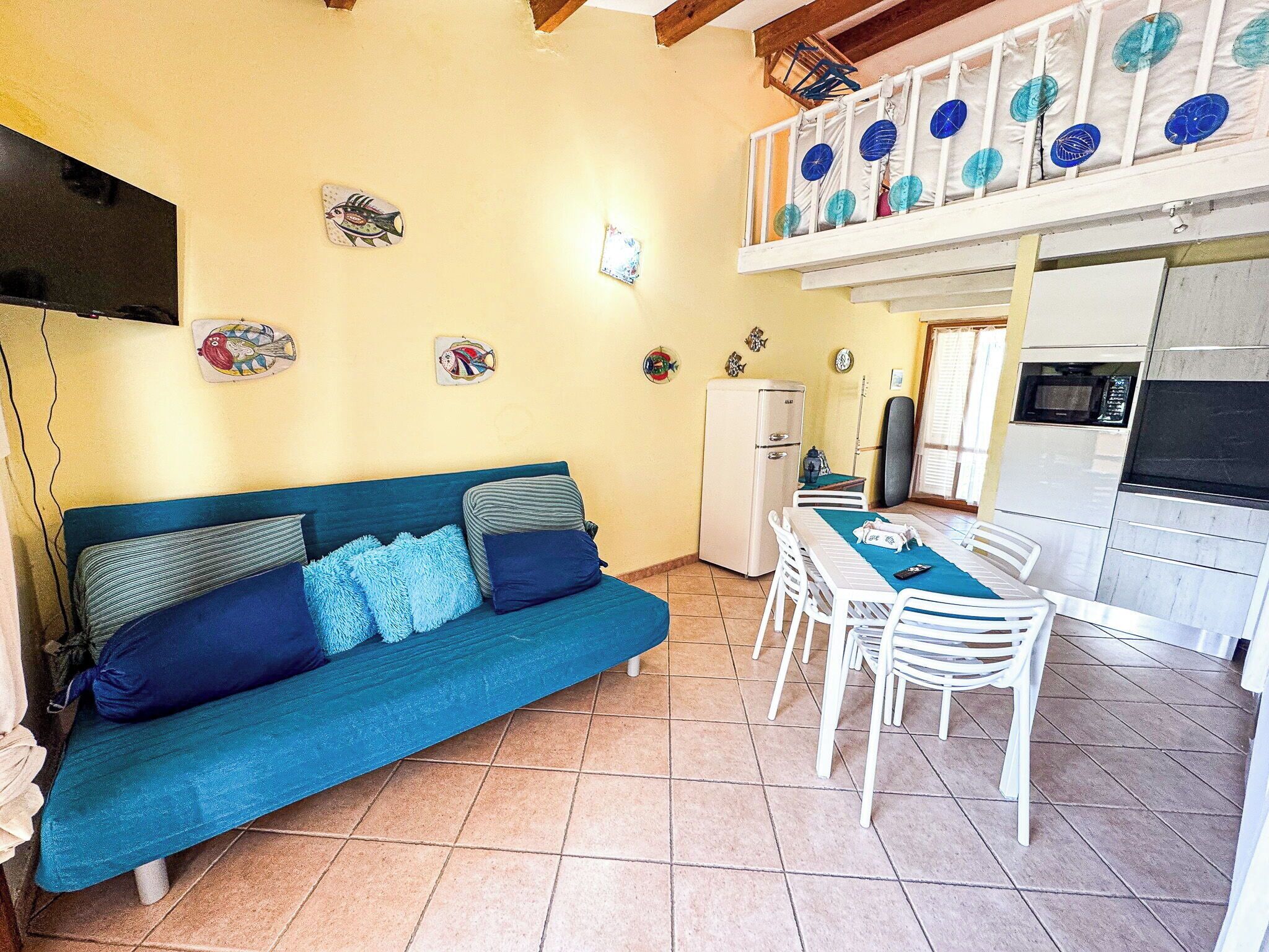 A cozy living area with a sofa, dining table, and chairs, a kitchen with appliances, and decorative fish wall art.