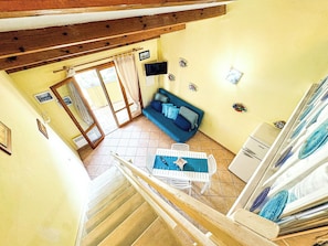 A room with a staircase, a sofa, a table, and a refrigerator. - Ostrica Apartment (Lumio)