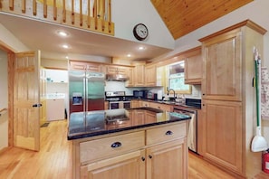 A spacious kitchen with wooden cabinets, a stainless steel refrigerator, a microwave, and a stove.