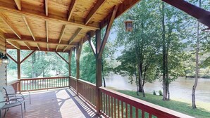 Une terrasse couverte avec vue sur une rivière et des arbres.