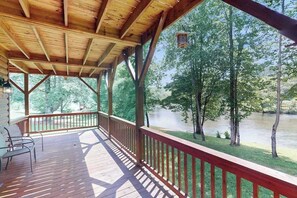 A covered deck with a view of a river and trees.