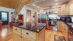 Une cuisine avec des meubles en bois, un réfrigérateur en acier inoxydable et un escalier en bois.