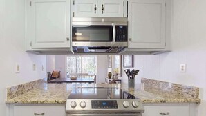 A kitchen with white cabinets, a stainless steel microwave, a stove, and granite countertops. - Two-story resort condo, pools, tennis, golf & lake access. Dog friendly (Sapphire)
