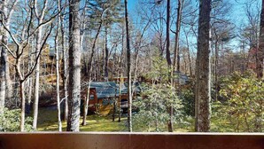 A wooden deck overlooking a forested area with a cabin. - Two-story resort condo, pools, tennis, golf & lake access. Dog friendly (Sapphire)