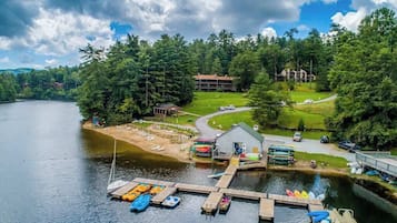 Un chalet au bord du lac, doté d’un quai, de bateaux et d’un bâtiment au toit rouge.