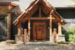 Eine Holzhütte mit Steinunterbau, einer Holzterrasse und einer Eingangstür.