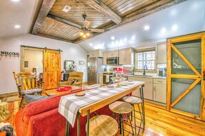 A kitchen with wooden beams, a bar area, and a large sliding door. - Stylish dog-friendly cottage with modern feel, fast WiFi, ideal location & more (Swannanoa)