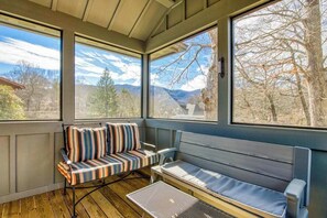 A sunroom with large windows, a cushioned bench, and a small table. - Stylish dog-friendly cottage with modern feel, fast WiFi, ideal location & more (Swannanoa)