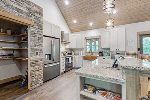 Eine moderne Küche mit Granit Arbeitsplatten, Edelstahlgeräten und einer Wand mit Steinverkleidung.
