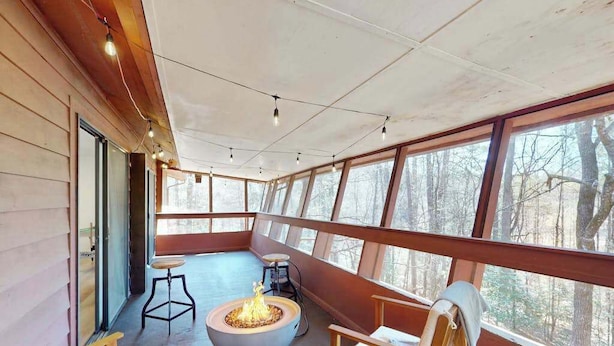 A cozy room with a fire pit, wooden furniture, and large windows offering a view of the forest. - Once Upon a Cabin, Mountain Views (Murphy)