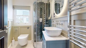 Ein modernes Badezimmer mit Duschkabine aus Glas, einem weißen Waschbecken und einer Toilette.