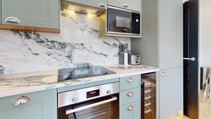 Eine Küche mit integriertem Mikrowellenherd, Backofen und Marmorarbeitsplatte.
