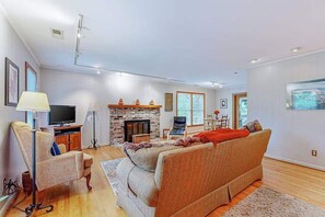 Ein modernes Wohnzimmer mit Sofa, Fernseher, Kamin und Essbereich.